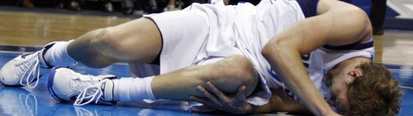 Dallas Mavericks forward Dirk Nowitzki lies on the floor holding his knee after sustaining an injury in the second half of their NBA basketball game in Dallas, Texas March 23, 2008. Nowitzki left the game and did not return.  REUTERS/Mike Stone (UNITED STATES)
